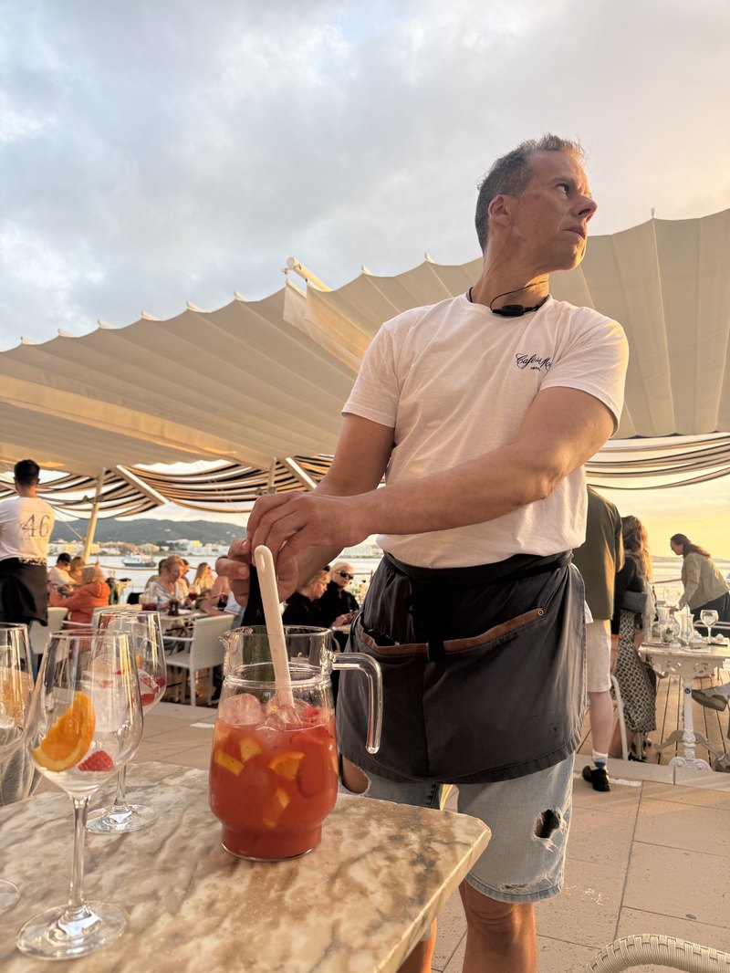 カフェ・デル・マールのテラスでサングリアを注ぐスタッフと夕暮れの海
