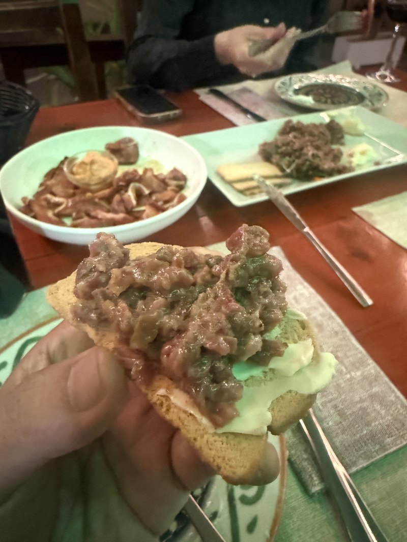 熱した石のプレートの上で焼く牛肉のステーキとフライドポテト・トングで取り分ける手