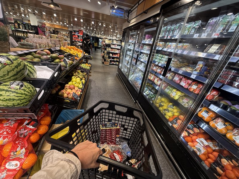 イビサのスーパーマーケットの店内・果物や野菜の棚とカートを押して買い出しする様子