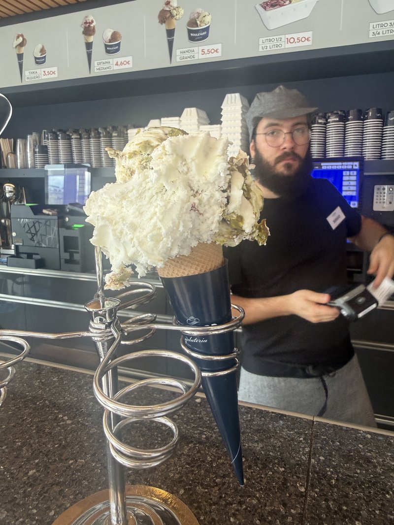 イタリア風アイスクリームの大盛りコーンを手にした店員