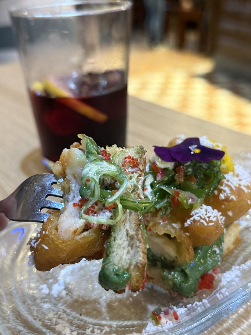 サングリアと並ぶ食用花と粉糖と緑のソースで彩られた芸術的なピンチョス