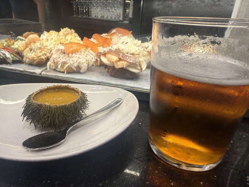 ウニの殻に入った濃いソースと冷えたビールの最初の一杯