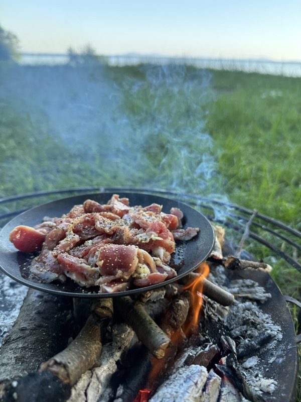 焚き火の鉄板で肉を焼く