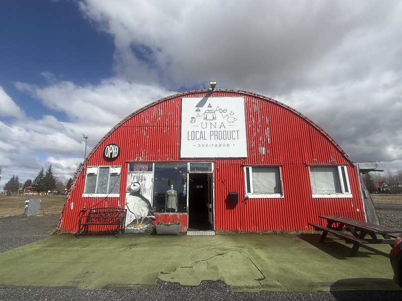 赤いカマボコ型の建物の地元産品店『UNA ローカルプロダクト』の外観