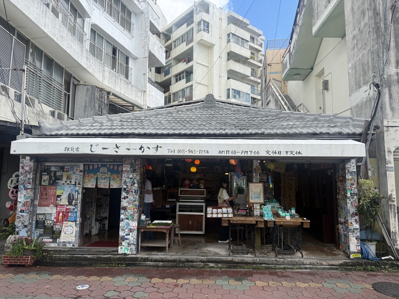壁一面にステッカーが貼られた、那覇の路地の雑貨店